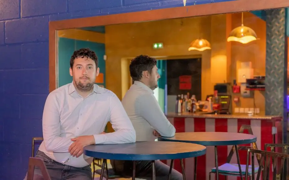 Matthieu Lancelot chemise claire est accoudée à une table de bistrot.